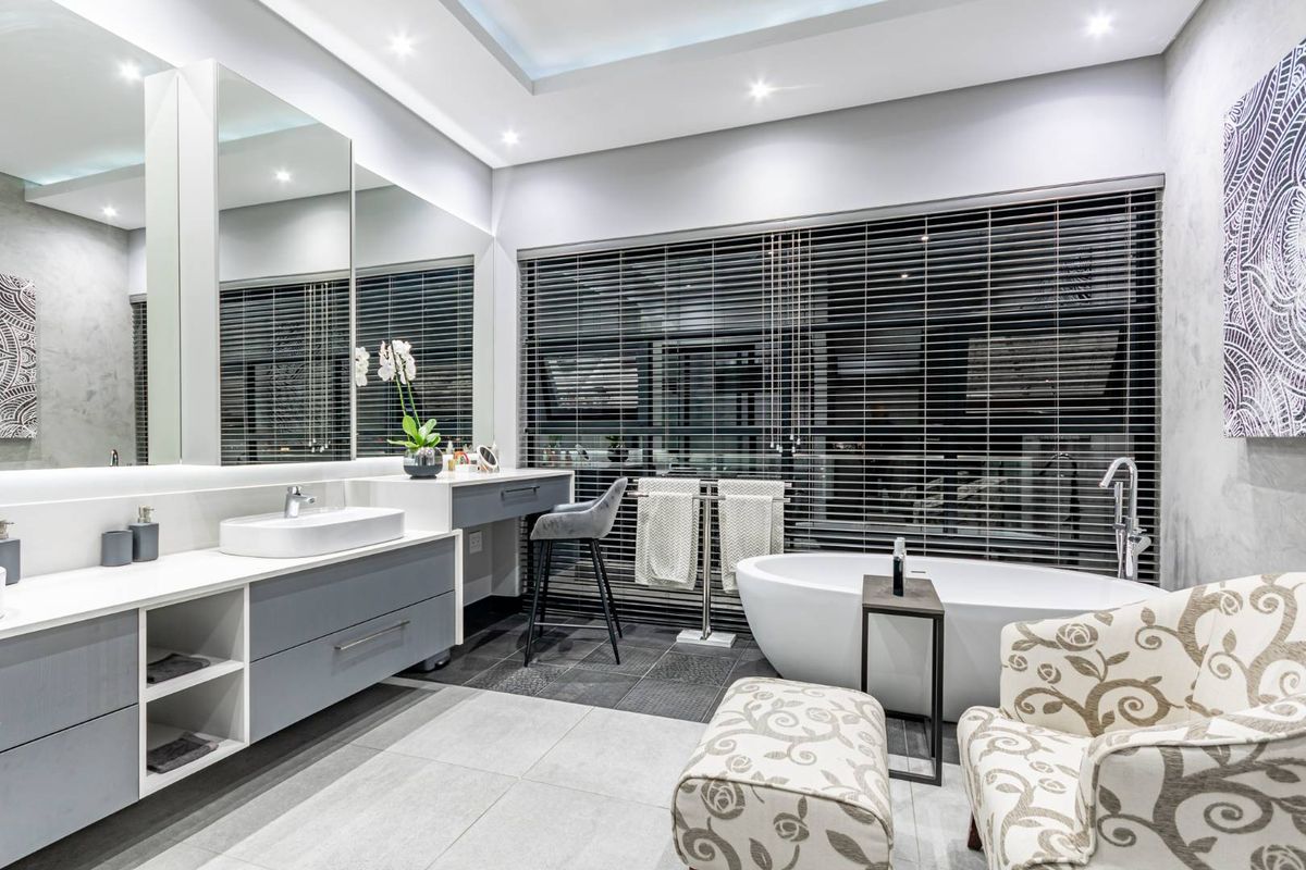 Modern, well-appointed bathroom featuring a sleek floating vanity with integrated basin, a contemporary freestanding bathtub, and large format floor tiles.