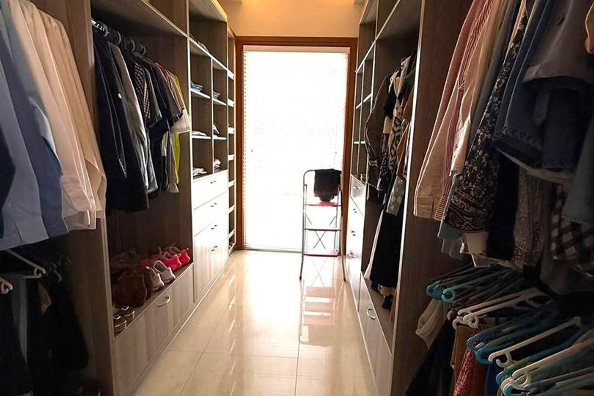 A walk-in closet featuring extensive built-in cabinetry, tiled flooring, and warm recessed ceiling lighting.