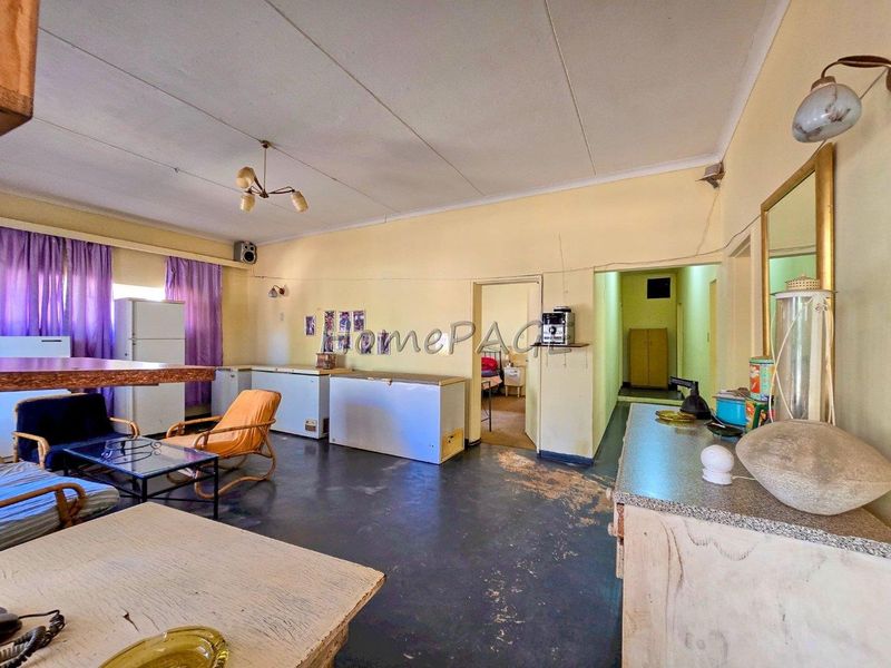 Spacious open-plan living area featuring tiled flooring and neutral wall finishes, offering potential for modernization and improved layout design.