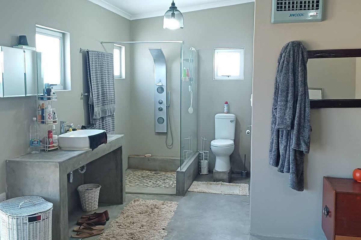 A modern bathroom featuring a concrete vanity, a walk-in shower with a rainfall shower panel, and a wall-mounted air cooler.