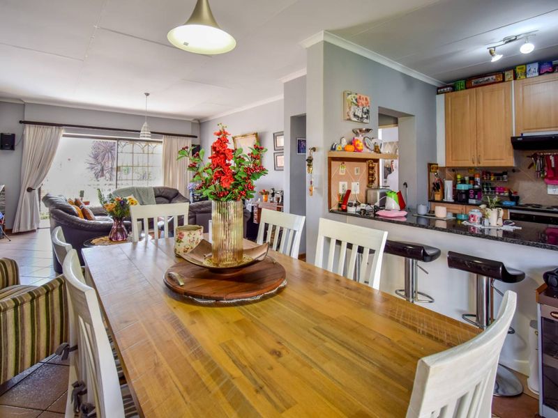 Open-plan living and dining area featuring a functional kitchen with granite countertops, breakfast bar, and direct access to the outdoor space via sliding doors.