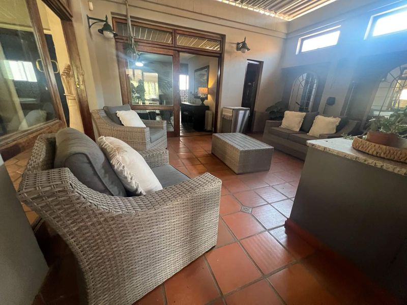 A covered patio area featuring terracotta floor tiles, timber-framed glass doors, and a built-in granite-topped counter, providing a comfortable outdoor living space.