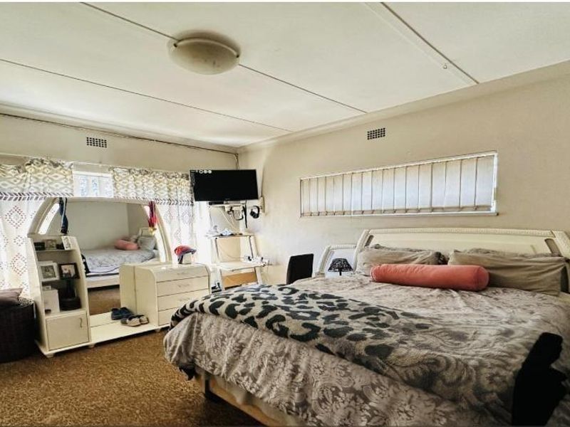Spacious bedroom featuring horizontal blinds, curtain rails, and a ceiling light fixture. The room requires cosmetic updates to improve its overall condition.