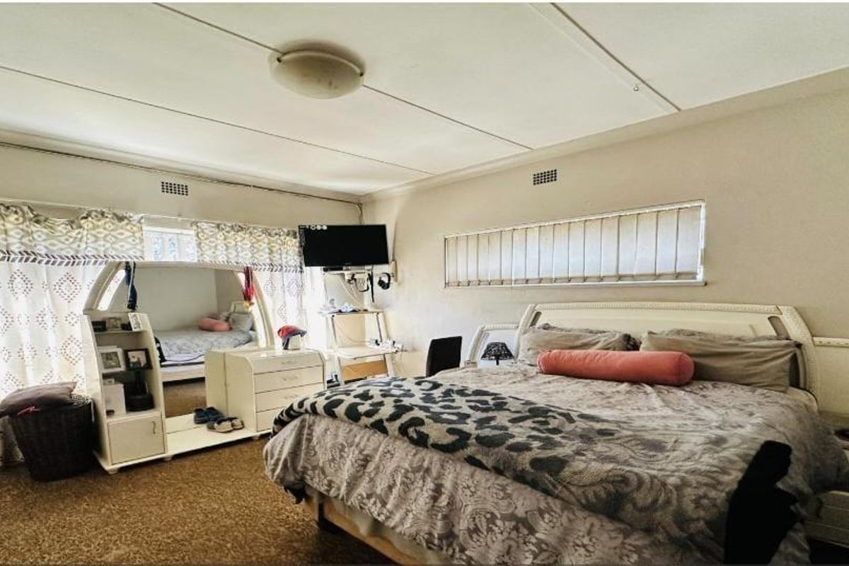 Spacious bedroom featuring horizontal blinds, curtain rails, and a ceiling light fixture. The room requires cosmetic updates to improve its overall condition.