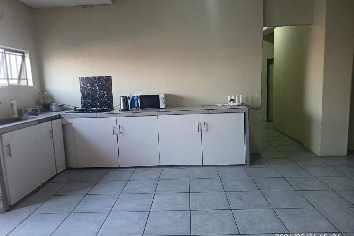 A functional kitchen area featuring tiled flooring, built-in cabinetry, and a hob, offering a blank canvas for potential cosmetic updates and modernization.