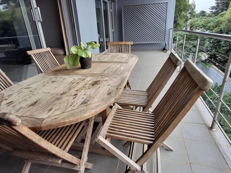 A spacious covered balcony featuring tiled flooring, a stainless steel balustrade, and large sliding glass doors providing seamless indoor-outdoor flow.