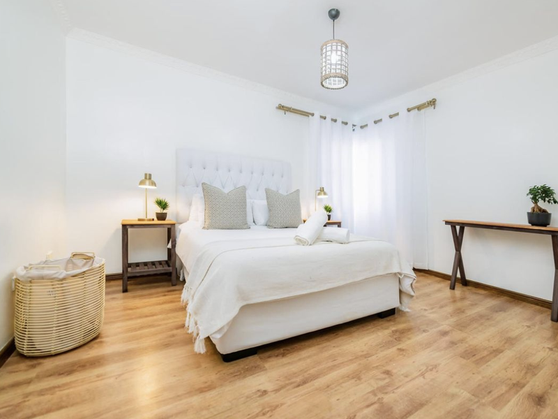 A bright and well-maintained bedroom featuring light wood-look laminate flooring and classic ceiling cornice detailing.