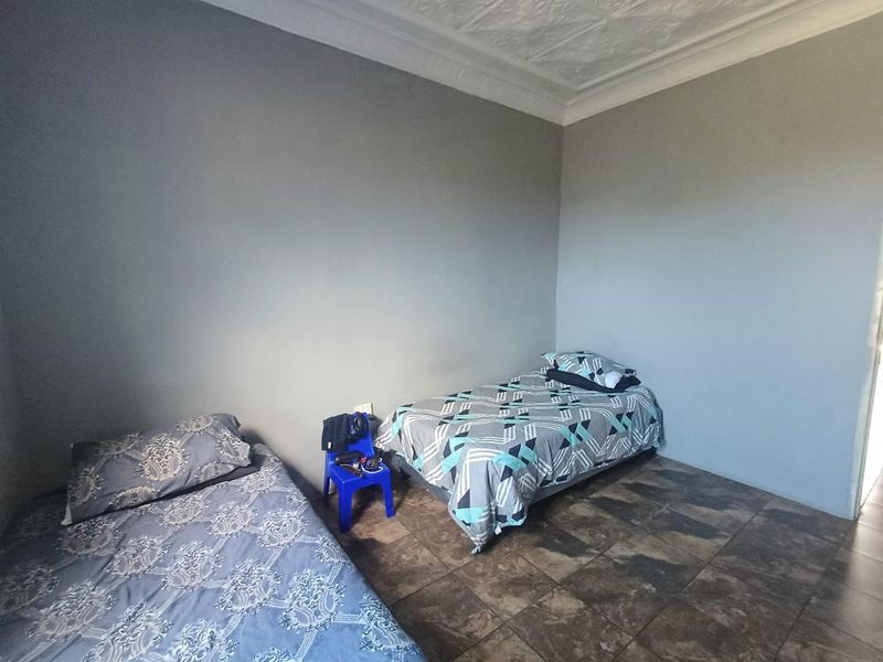 A bedroom featuring tiled flooring and decorative ceiling cornicing, providing a neutral base for potential interior design updates.