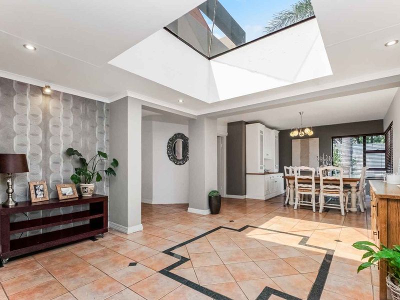 Spacious open-plan living and dining area featuring a large central skylight, tiled flooring, and neutral contemporary finishes.
