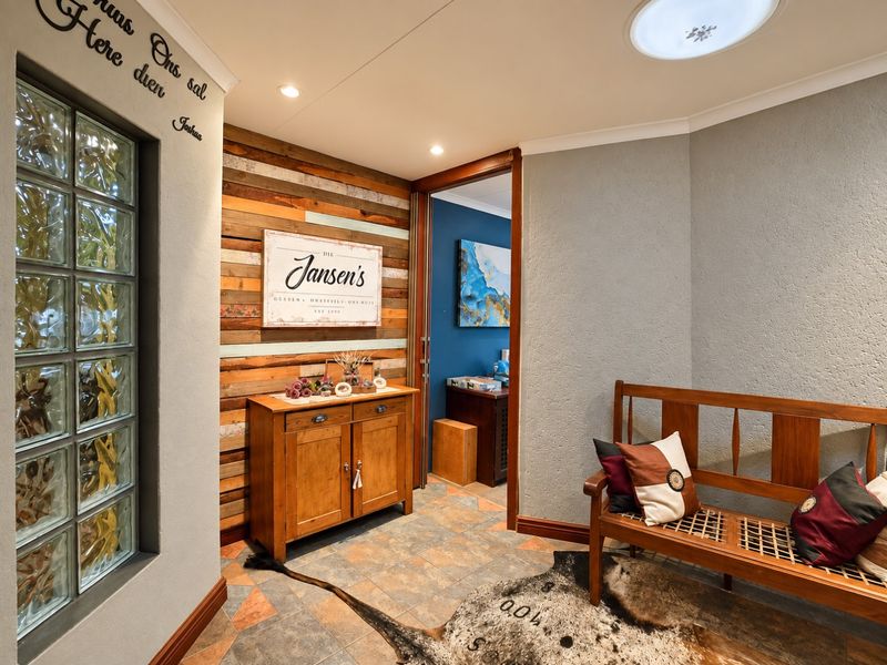 A well-maintained hallway featuring textured walls, decorative timber cladding, a glass block window, and tiled flooring with recessed ceiling lighting.