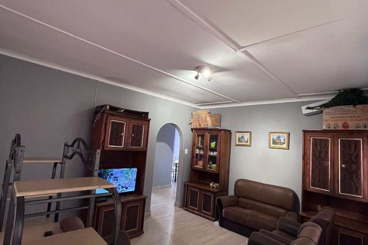 A living room featuring tiled flooring, arched doorway access, and neutral wall tones, providing a functional and traditional living space.