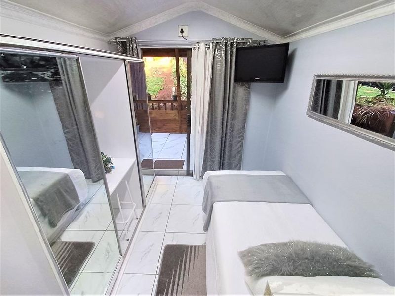 Compact bedroom featuring tiled flooring, a built-in mirrored wardrobe, and direct access to an outdoor patio area through a sliding glass door.