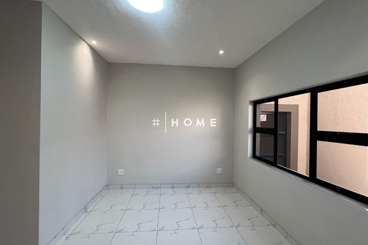 A clean, empty bedroom featuring modern white marble-look floor tiles, black aluminium window frames, and recessed ceiling lighting.