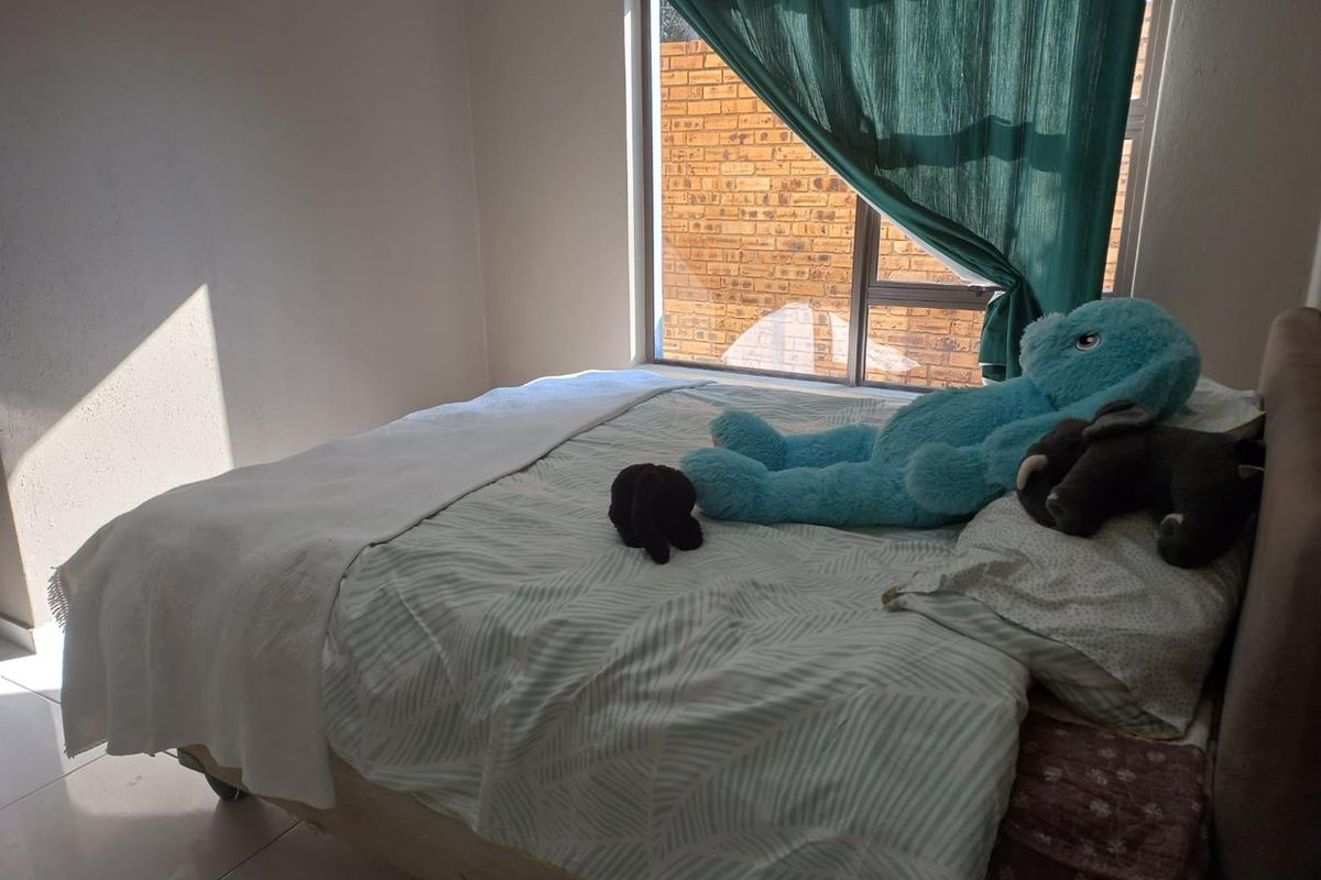 A bedroom featuring tiled flooring and a large window allowing natural light, providing a functional space for rest.