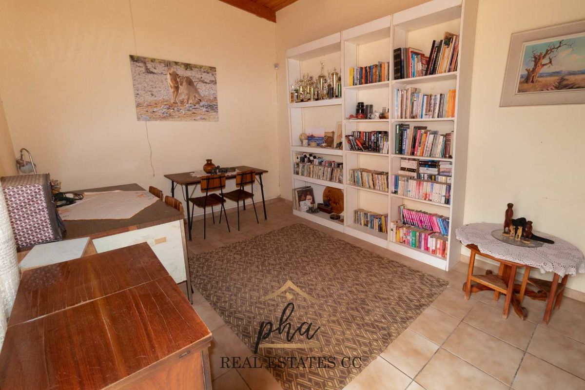 A living area featuring built-in floor-to-ceiling shelving units and tiled flooring, providing functional storage space within the room.
