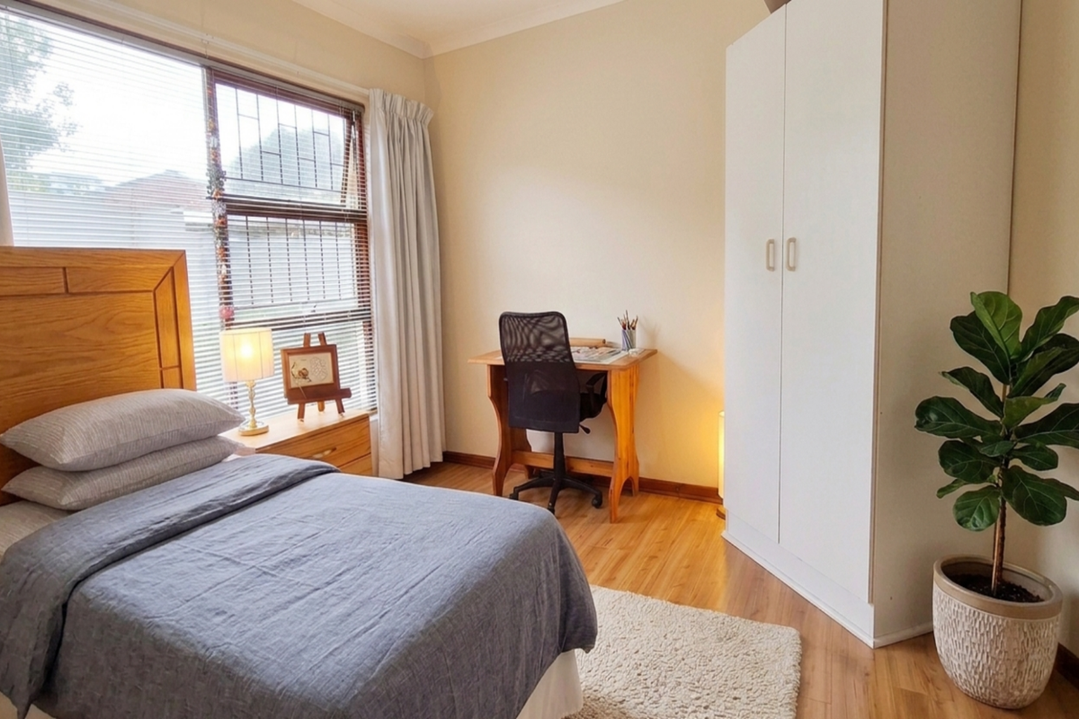 A well-lit bedroom featuring laminate flooring, a large window with security bars, and a built-in wardrobe.
