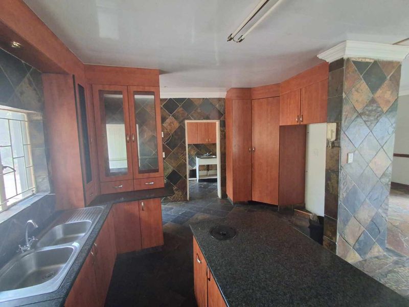 Spacious kitchen featuring extensive built-in cabinetry, granite countertops, a central island, and distinctive slate wall and floor tiling throughout.