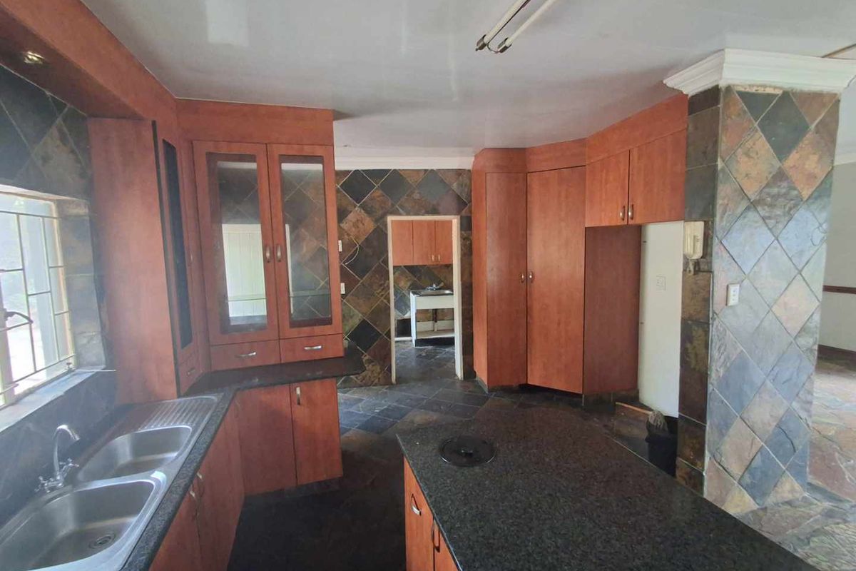 Spacious kitchen featuring extensive built-in cabinetry, granite countertops, a central island, and distinctive slate wall and floor tiling throughout.