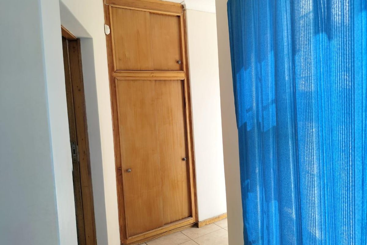 A bedroom interior featuring a built-in wooden cupboard and tiled flooring, presenting a clean, empty space ready for personalization.