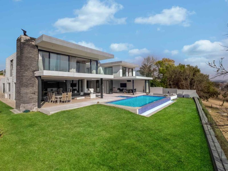 Modern double-story residence featuring a spacious covered patio, swimming pool, and landscaped garden with contemporary stone cladding and expansive glass sliding doors.