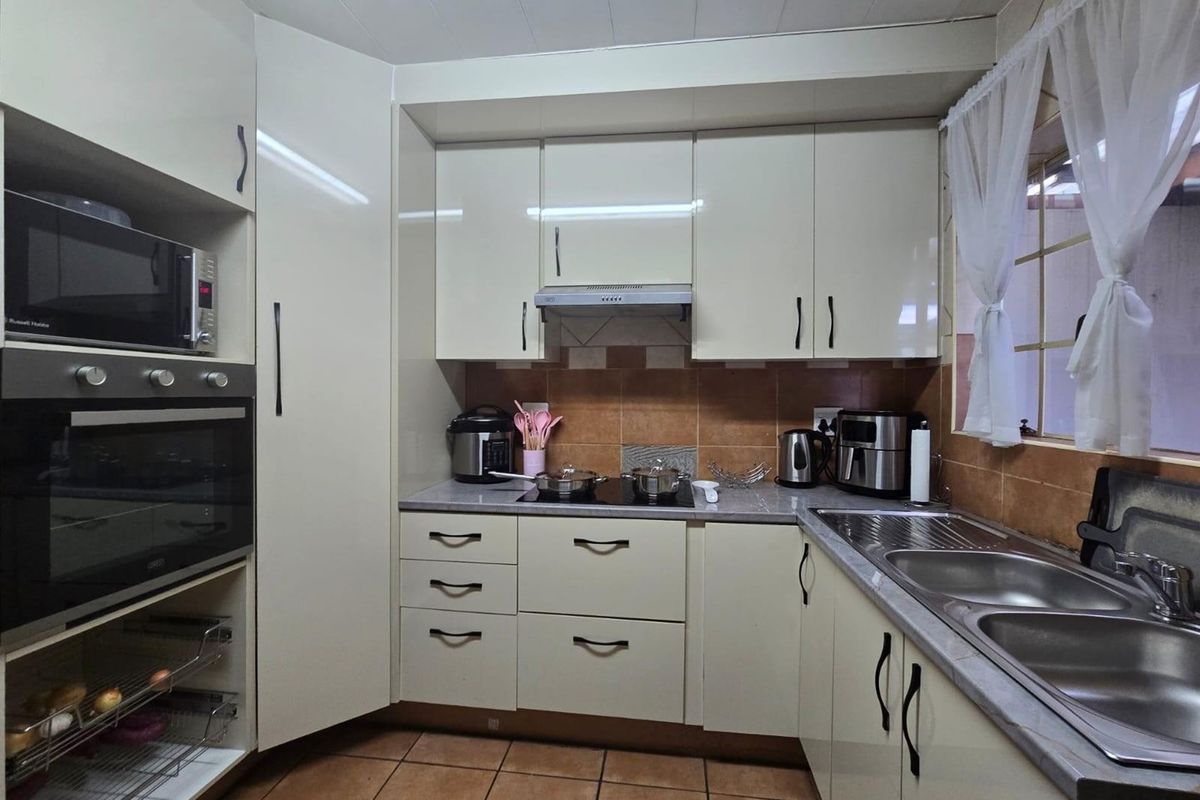 A functional kitchen featuring built-in cabinetry, an integrated oven, hob with extractor fan, and a double bowl sink with tiled splashback.