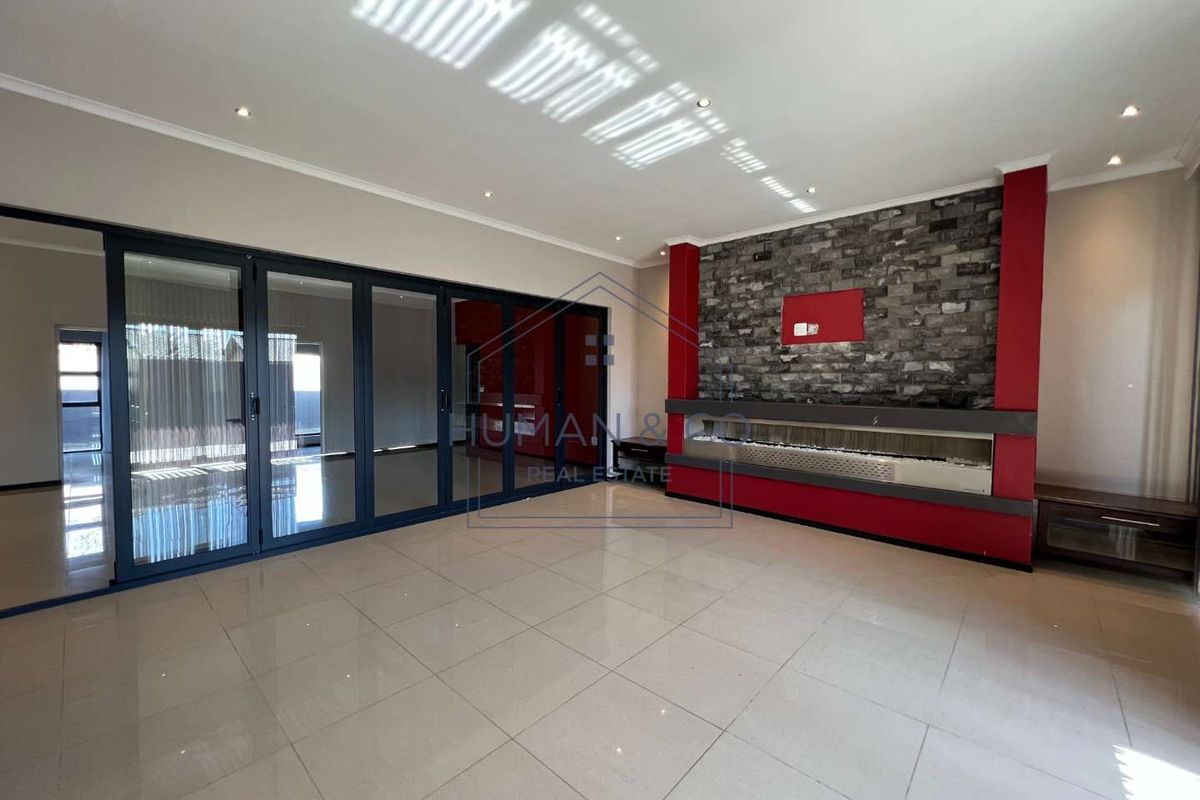 Spacious living area featuring large glass sliding doors, tiled flooring, and a prominent stone-clad feature wall with a built-in fireplace.