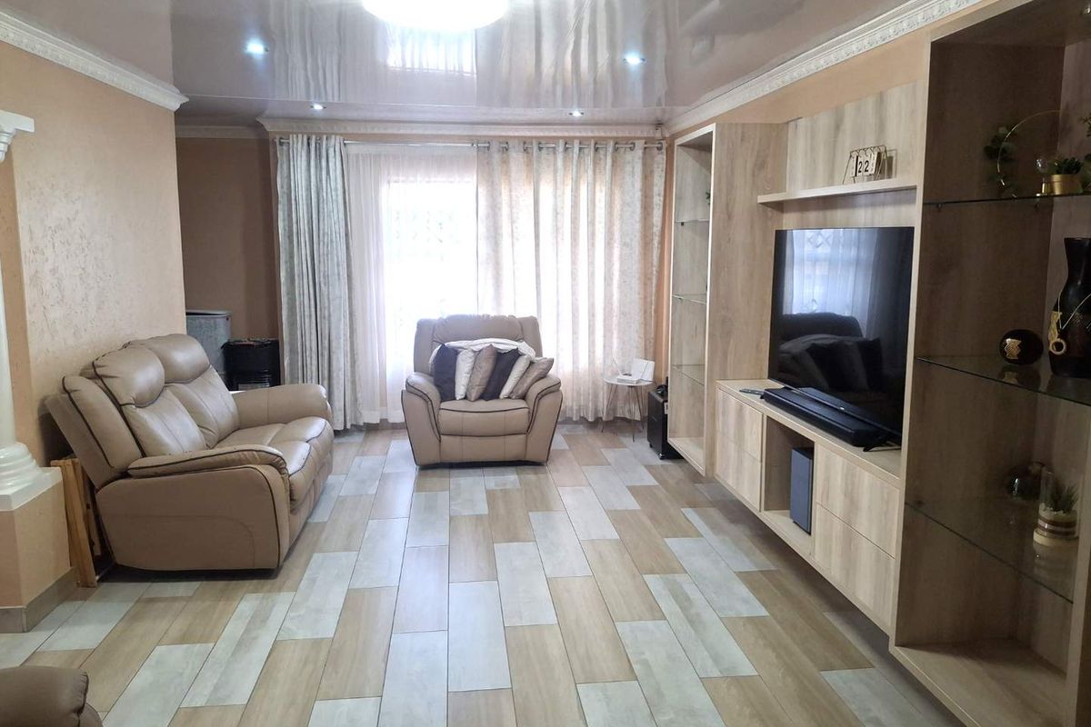 A well-maintained living room featuring built-in cabinetry, modern tiled flooring, and a glossy ceiling finish with integrated lighting.