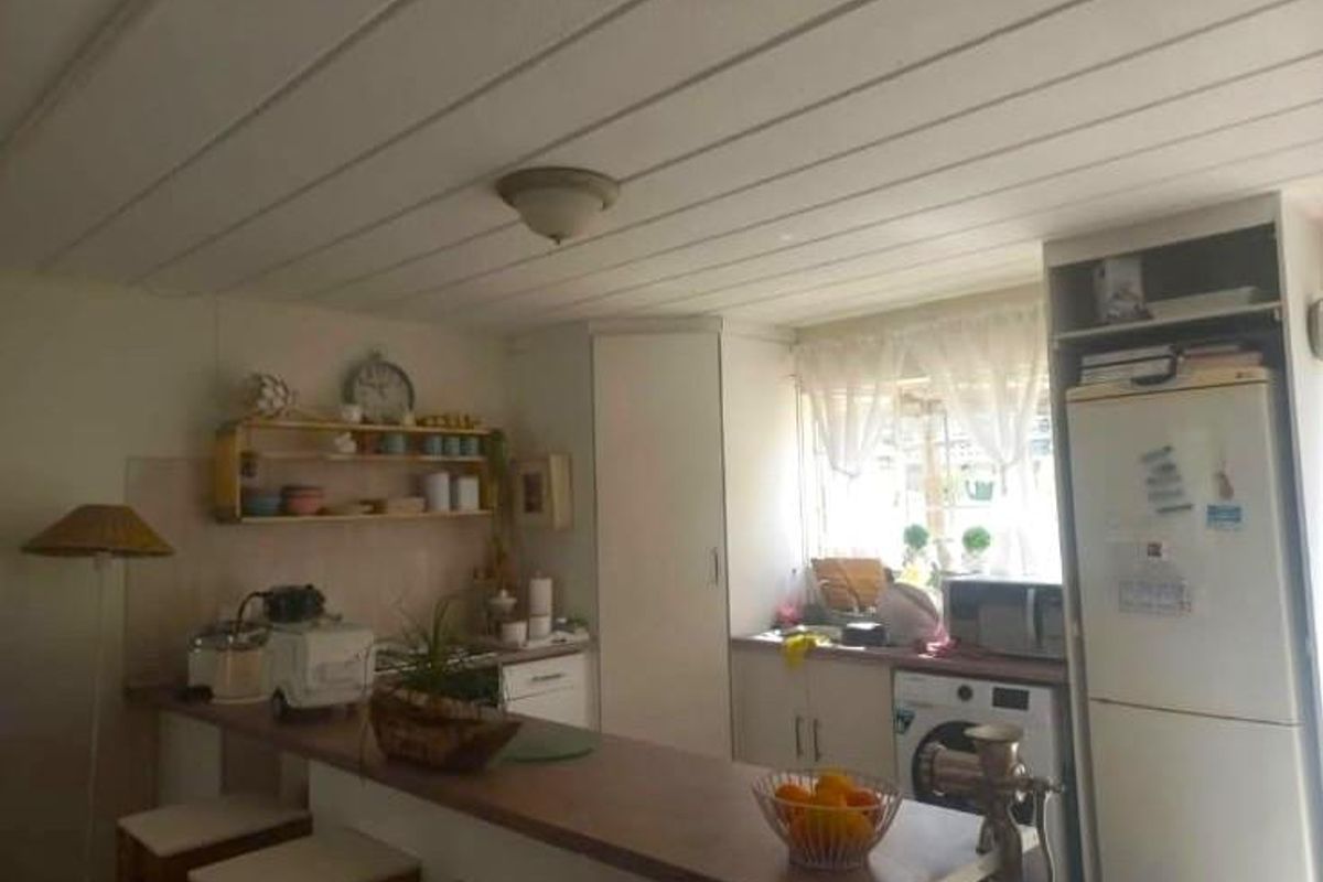 A functional kitchen featuring built-in cabinetry, a breakfast bar, and a tiled backsplash, offering a practical layout for daily meal preparation.