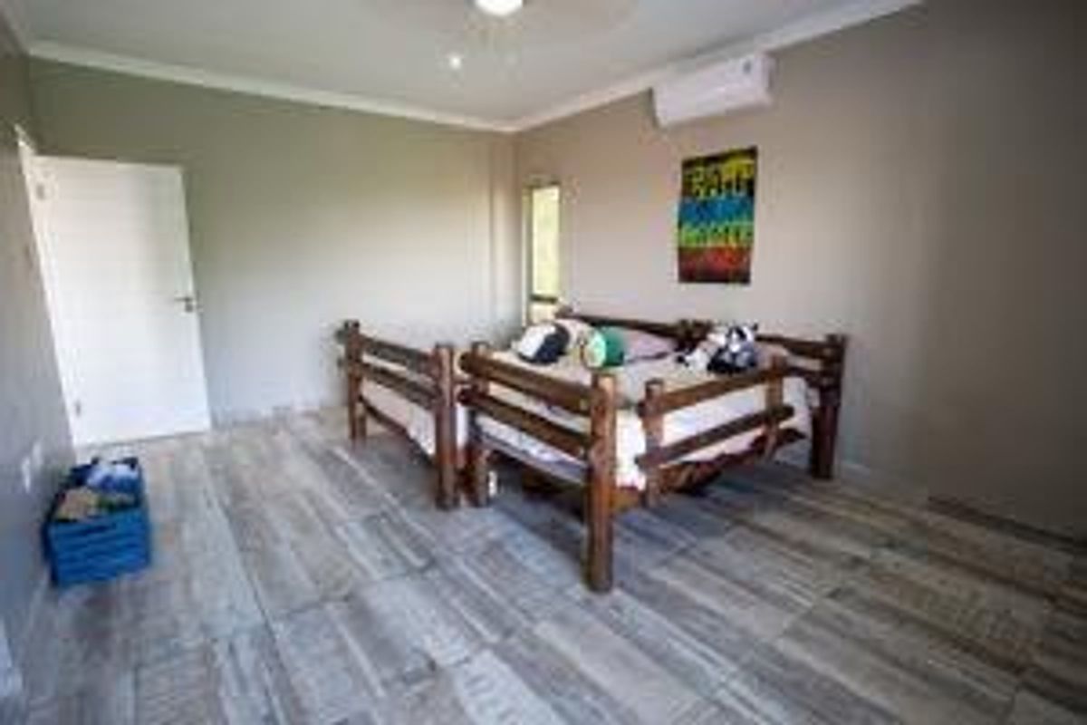 A bedroom featuring wood-look tile flooring, a wall-mounted air conditioning unit, and a ceiling fan.