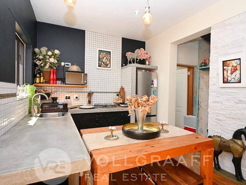Modern kitchen featuring concrete countertops, gas hob, tiled backsplash, and a distinctive stone veneer feature wall, offering a contemporary industrial aesthetic.