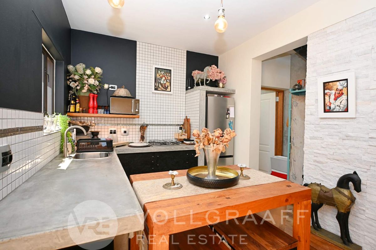 Modern kitchen featuring concrete countertops, gas hob, tiled backsplash, and a distinctive stone veneer feature wall, offering a contemporary industrial aesthetic.