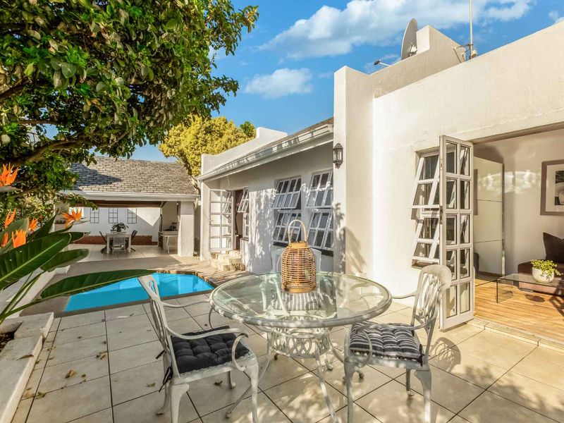 A sunny outdoor patio area featuring tiled flooring, direct access to the interior, and a view of the adjacent swimming pool.