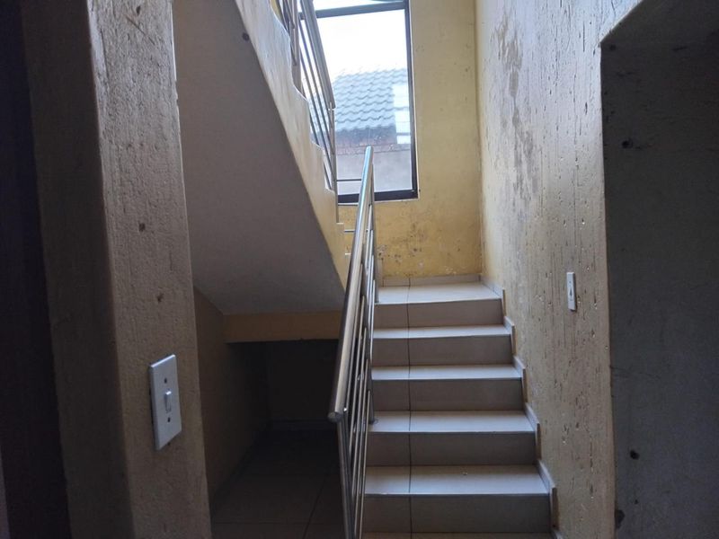 Interior staircase area featuring tiled steps and a stainless steel balustrade, requiring cosmetic wall repairs and painting to improve the overall condition.
