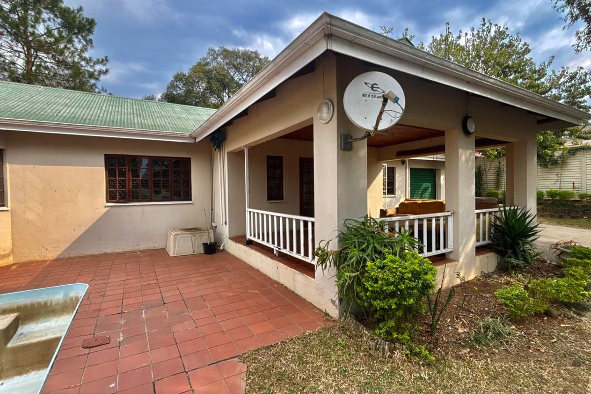 Rear view of the house featuring a covered veranda, terracotta tiled patio area, and established garden surroundings.