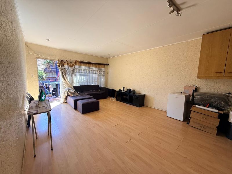 Spacious living area featuring laminate flooring, textured walls, and built-in cabinetry, with direct access to an outdoor patio area.