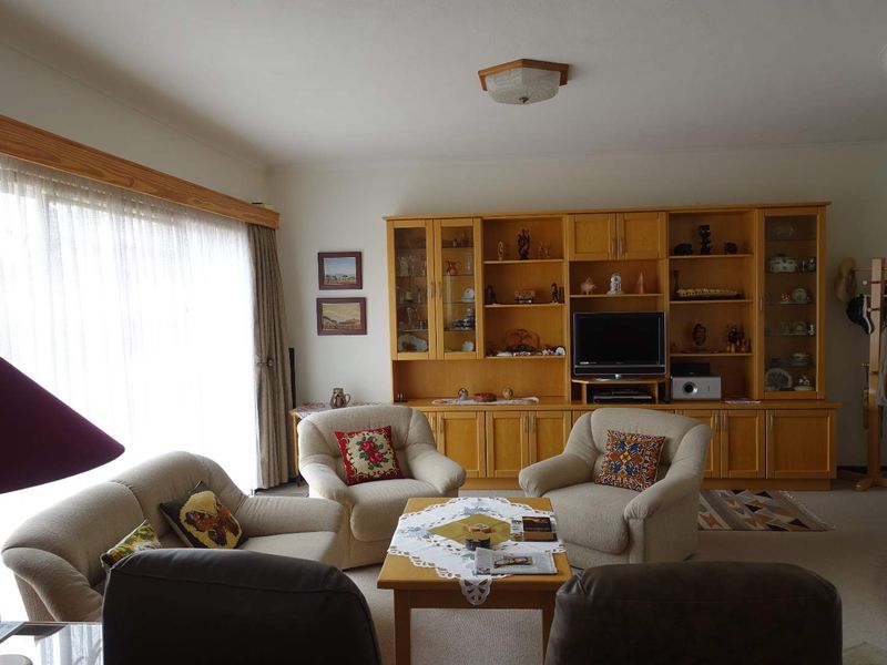 A spacious living room featuring extensive built-in wooden cabinetry and large sliding glass doors that provide ample natural light.