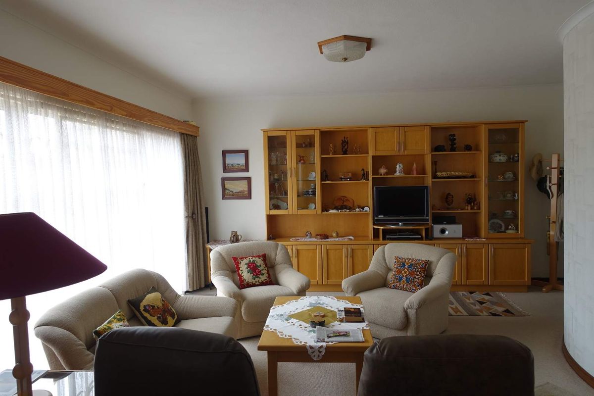 A spacious living room featuring extensive built-in wooden cabinetry and large sliding glass doors that provide ample natural light.