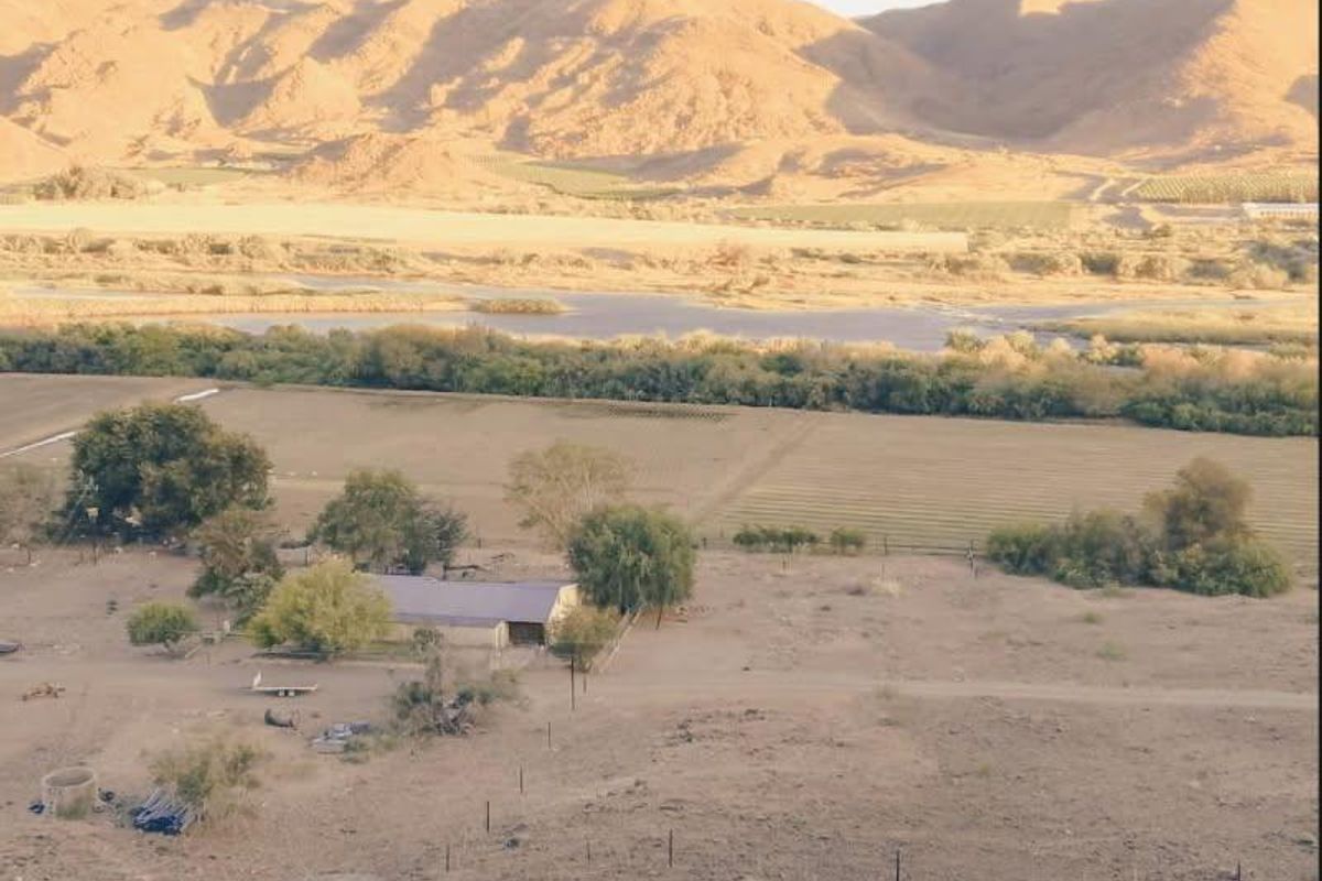 Aerial view of the small holding property featuring expansive open land, agricultural fields, and a rural dwelling set against a scenic mountain backdrop.