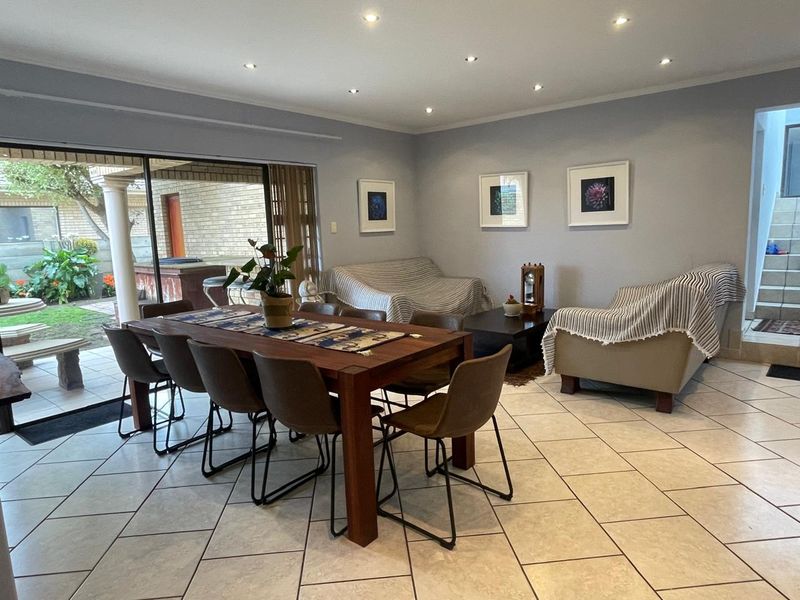 Open plan living and dining area featuring tiled flooring, recessed downlighting, and large sliding glass doors providing direct access to the outdoor patio.