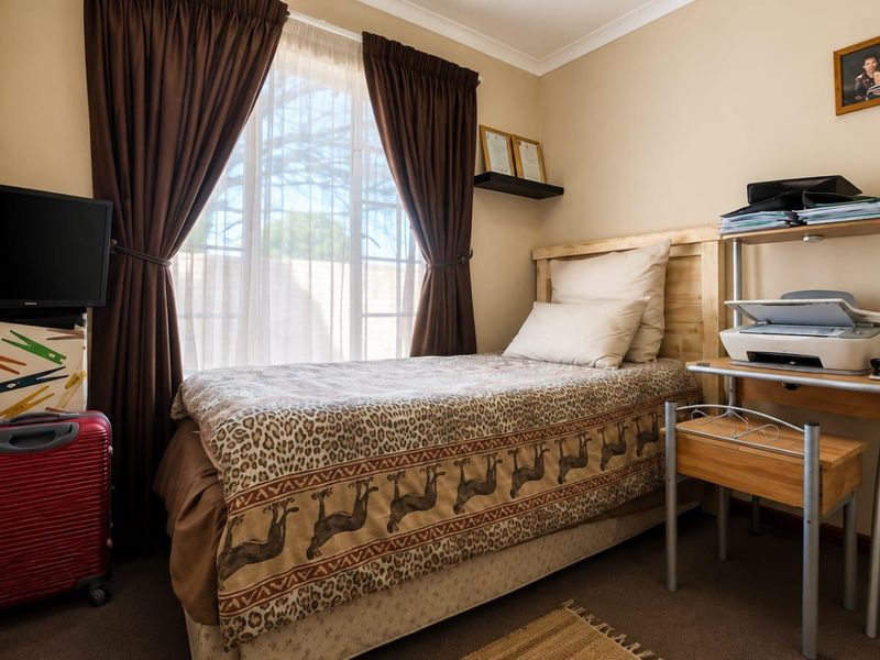 A cozy bedroom featuring carpeted flooring, neutral wall tones, and a window with curtains, providing a comfortable and functional living space.