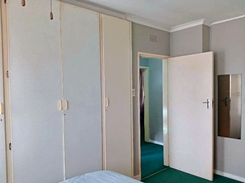 Bedroom featuring built-in cupboards, coving, and access to an adjoining room with green carpeting.