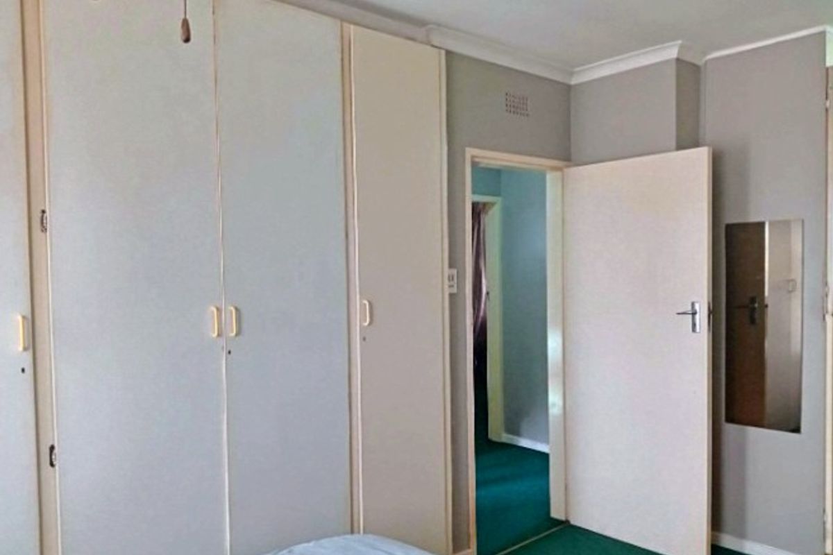 Bedroom featuring built-in cupboards, coving, and access to an adjoining room with green carpeting.