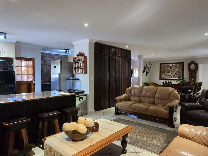 Spacious open-plan living area featuring a kitchen with granite countertops, tiled flooring, and a distinct exposed brick wall, creating a functional family space.