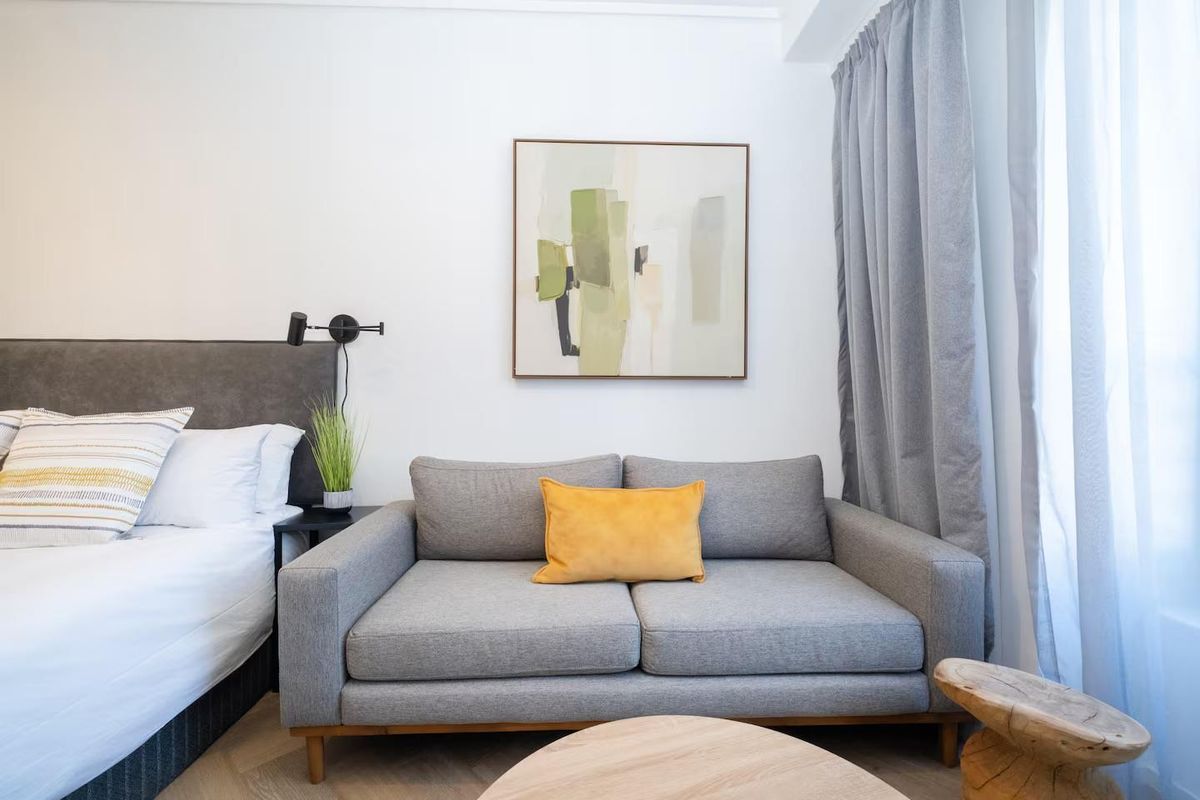 A well-appointed bedroom featuring modern herringbone flooring and a sleek wall-mounted reading light, creating a comfortable and contemporary living space.