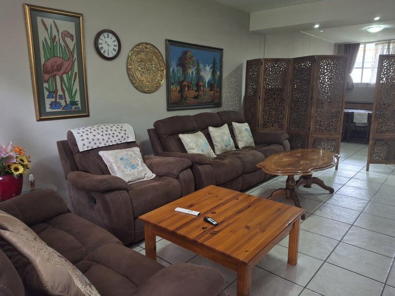 A spacious living area featuring neutral wall tones, tiled flooring, and recessed downlighting, offering a comfortable and functional layout.