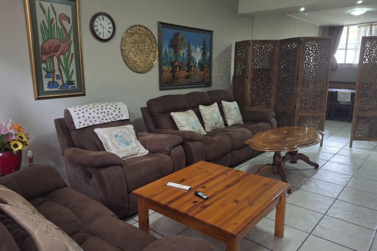 A spacious living area featuring neutral wall tones, tiled flooring, and recessed downlighting, offering a comfortable and functional layout.