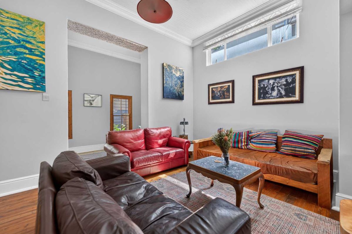 A spacious living room featuring high ceilings, hardwood flooring, and clerestory windows that provide ample natural light.