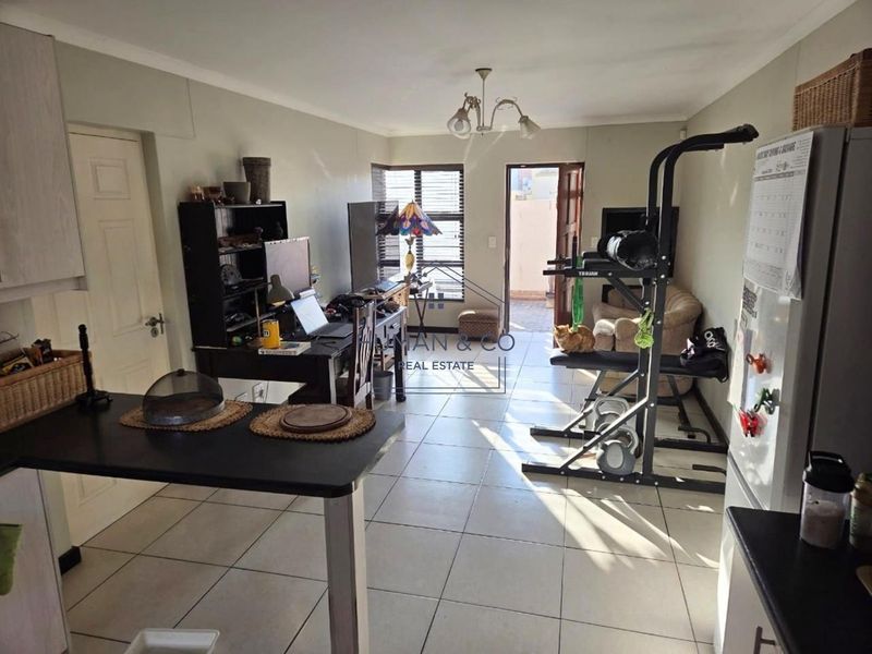 Open-plan living area featuring tiled flooring, kitchen cabinetry, and direct access to an outdoor space.