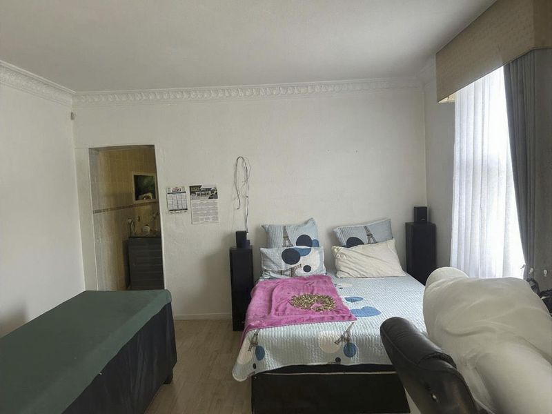 A bedroom featuring crown molding, laminate flooring, and an attached en-suite bathroom area.