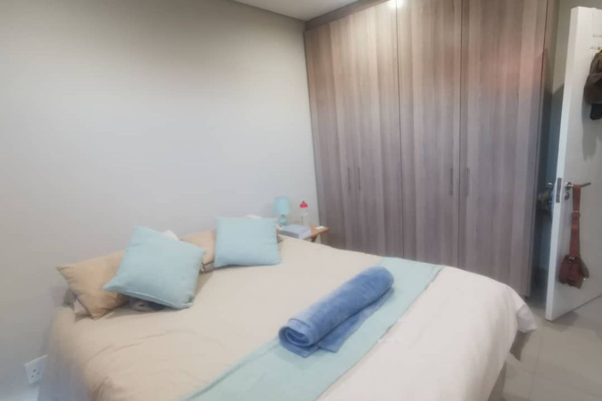 A well-maintained bedroom featuring neutral wall tones, tiled flooring, and extensive built-in wooden cupboards providing ample storage space.